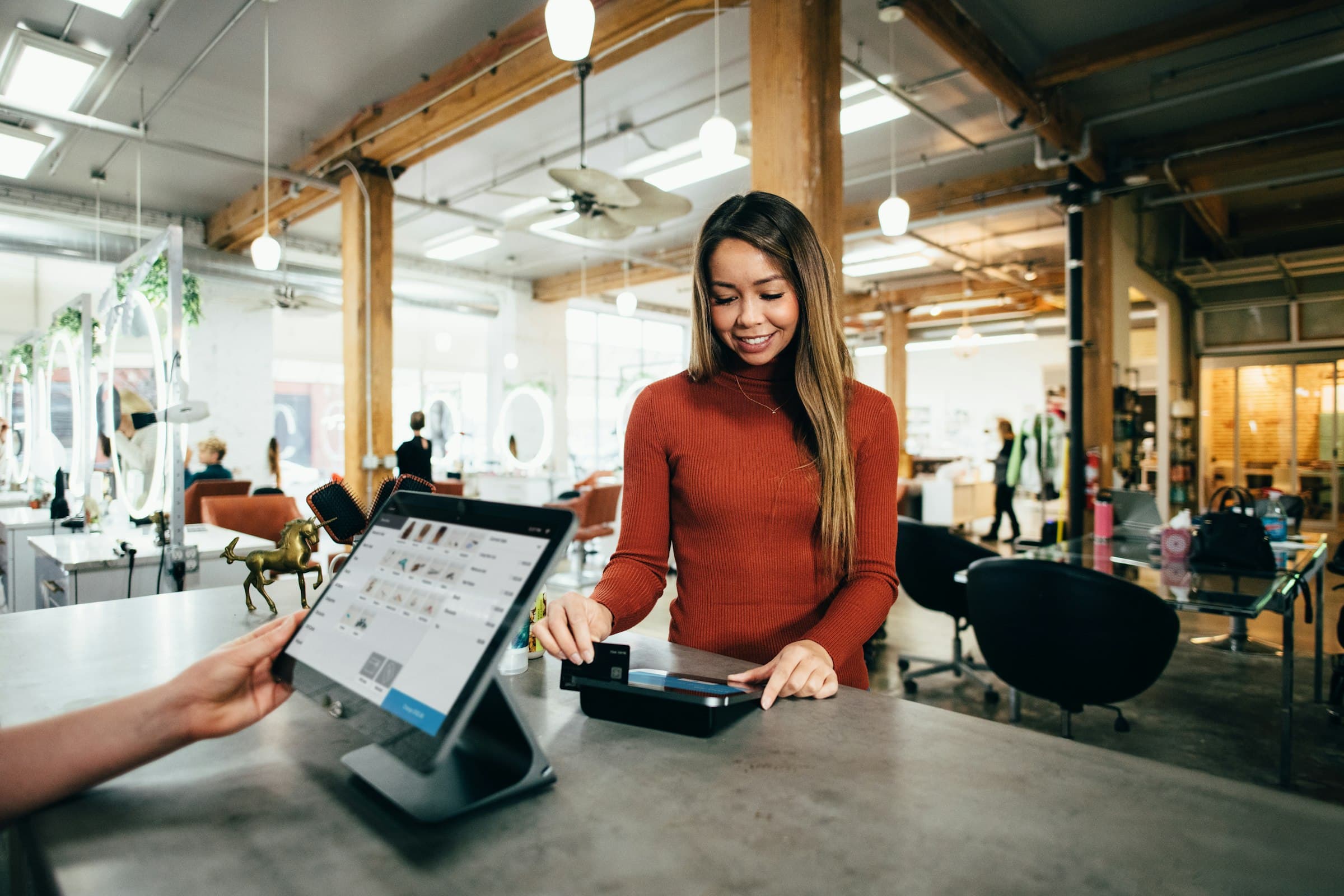 A customer paying by card at a shop counter with a tablet point of sale.